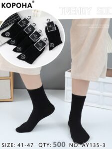 Desk with leather desk pad, walnut desk organizer, wireless keyboard and mouse, and porcelain mug.